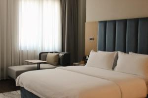 a hotel room with a large bed and a chair at Paziro Hotel in Dushanbe