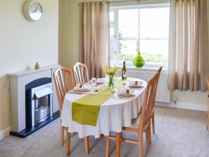 a dining room with a table and chairs and a fireplace at California Halt in Scratby