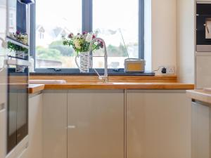a kitchen with a sink and a window with flowers at Wrens Perch in Brixham +19 photos