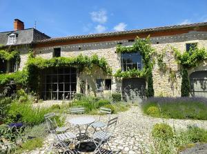 a patio with a table and chairs in front of a building at LA CLE d'ESCAMPS in Escamps