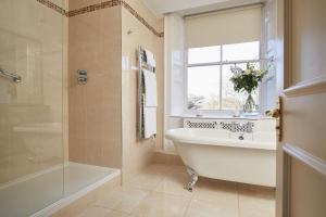 a bathroom with a tub and a sink and a window at Macdonald Leeming House in Watermillock +37 photos