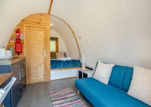 a living room with a blue couch and a kitchen at Apple Mount Retreat in Preston