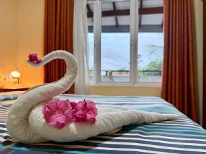 a towel swans are sitting on a bed with flowers at Judewin villa Negombo in Negombo