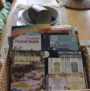 a pile of magazines and newspapers on a table at Willow View Streamside Retreat near Kynren Durham in Newton Aycliffe