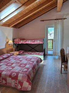 a bedroom with two beds and a window at Hotel Villa Cima Undici in Pozza di Fassa +35 photos