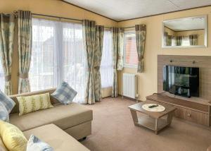 a living room with a couch and a tv at Whitehouse Holiday Park in Abergele
