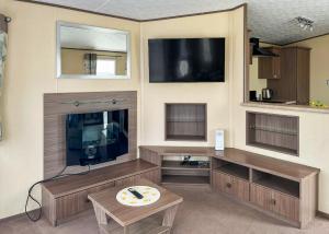 a living room with a tv and a table at Whitehouse Holiday Park in Abergele
