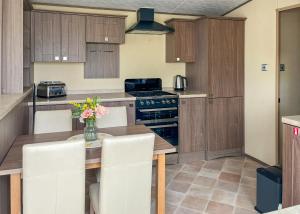 a kitchen with a table with a vase of flowers on it at Whitehouse Holiday Park in Abergele