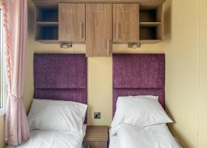 a bedroom with two beds and a purple headboard at Whitehouse Holiday Park in Abergele
