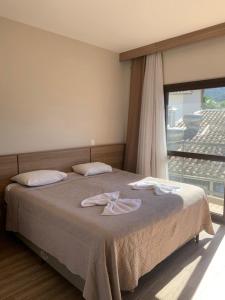 a bedroom with a large bed with a large window at Tons de Mar Apart Hotel in Ubatuba