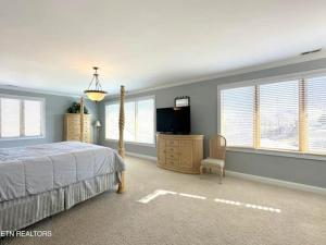 a bedroom with a bed and a tv and windows at Cove Manor in Maynardville +7 photos