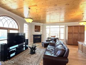 a living room with a leather couch and a flat screen tv at Cove Manor in Maynardville