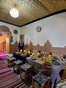 a woman standing in a room with two tables and chairs at Dar Bani in Zagora