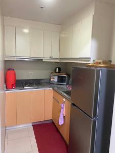 a kitchen with a stainless steel refrigerator and cabinets at Cozy condo unit at The Palladium in Iloilo City