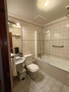 a bathroom with a toilet and a tub and a sink at Hotel Isla Rey Jorge in Punta Arenas