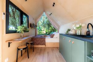 a tiny house with a bed and a kitchen with a sink at La Tiny sous les pins in Noves
