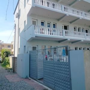 a white house with a fence and a balcony at Beach Guest House in Durrës