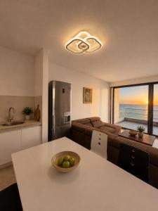 a kitchen and living room with a table with a bowl of fruit at Vila Maxim in Marovići