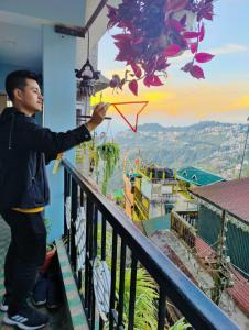 a man standing on a balcony holding a kite at Mysa Maya Homestay 12Mins Walk to Mall Road in Darjeeling