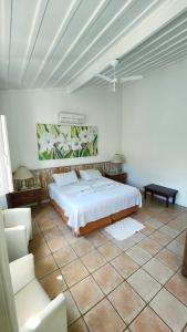 a white bedroom with a bed and a chair at Pousada Lacosta in Ilhabela