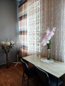 a dining room table with a vase of feathers on it at Tosmare Apartament in Liepāja