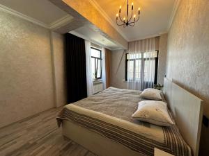 a bedroom with a bed with pillows and a chandelier at Caspian Boulevard Residence in Sumqayıt
