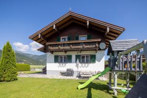 a house with a wooden roof and a playground at Familienparadies - Chalet Hoamatl in Achenkirch +8 photos