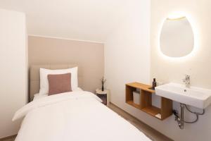 a bedroom with a white bed and a sink at Familienparadies - Chalet Hoamatl in Achenkirch