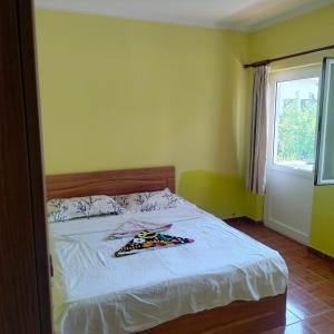 a bedroom with a bed with white sheets and a window at Beach Guest House in Durrës