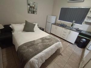 a bedroom with a large bed and a desk at Serendipity Guest House in Richards Bay