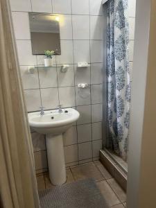 a white bathroom with a sink and a shower at Serendipity Guest House in Richards Bay