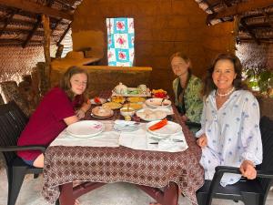 three women sitting at a table eating food at Sigiriya Carpenter Cottage in Sigiriya