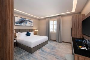 a hotel room with a bed and a flat screen tv at Warwick Al Baha Hotel in Baljurashi