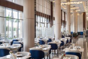 a dining room with tables and chairs and windows at Warwick Al Baha Hotel in Baljurashi