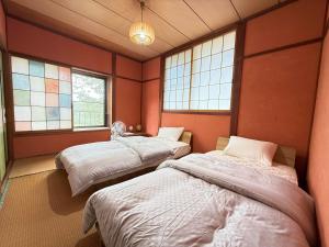 two beds in a room with two windows at Guest house AZSINN in Ueda