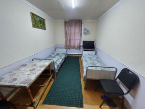 a room with two beds and a table and a chair at Umid Hostel in Termiz