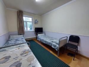 a room with two beds and a chair in it at Umid Hostel in Termiz
