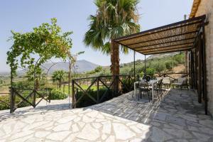 an outdoor patio with a table and chairs and palm trees at Mulino 1220 in Scopello