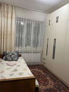 a bedroom with a bed and white cabinets and a window at Keremeti guest house in Dzhangyaryk