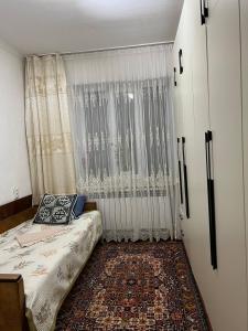 a bedroom with a bed and a large window at Keremeti guest house in Dzhangyaryk