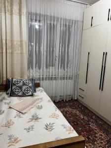 a bedroom with a bed and a dresser and curtains at Keremeti guest house in Dzhangyaryk