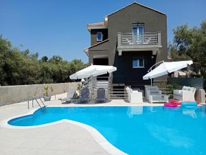 a house with a swimming pool with chairs and umbrellas at Alivka Apartments in Apolpaina