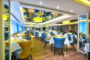 ein Restaurant mit weißen Tischen und blauen Stühlen in der Unterkunft Grace21 Runway Hotel in Dhaka