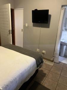 a bedroom with a bed and a flat screen tv on the wall at Serendipity Guest House in Richards Bay