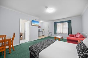 a hotel room with a bed and a couch and a table at Maynestay Motel in Gunnedah