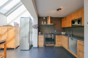 a kitchen with a white refrigerator and wooden cabinets at Villa Mooy met sauna - Landal park Ooghduyne Julianadorp aan Zee in Julianadorp