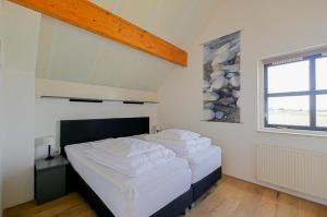 a bedroom with two beds with white sheets and a window at Villa Mooy met sauna - Landal park Ooghduyne Julianadorp aan Zee in Julianadorp