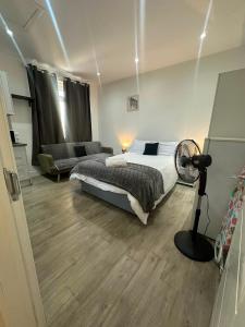 a bedroom with a bed and a fan and a couch at Wimbledon Family Studio Flat 1 in London