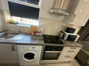 a kitchen with a sink and a washing machine at Wimbledon Family Studio Flat 1 in London +3 photos