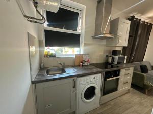 a kitchen with a sink and a washing machine at Wimbledon Family Studio Flat 1 in London